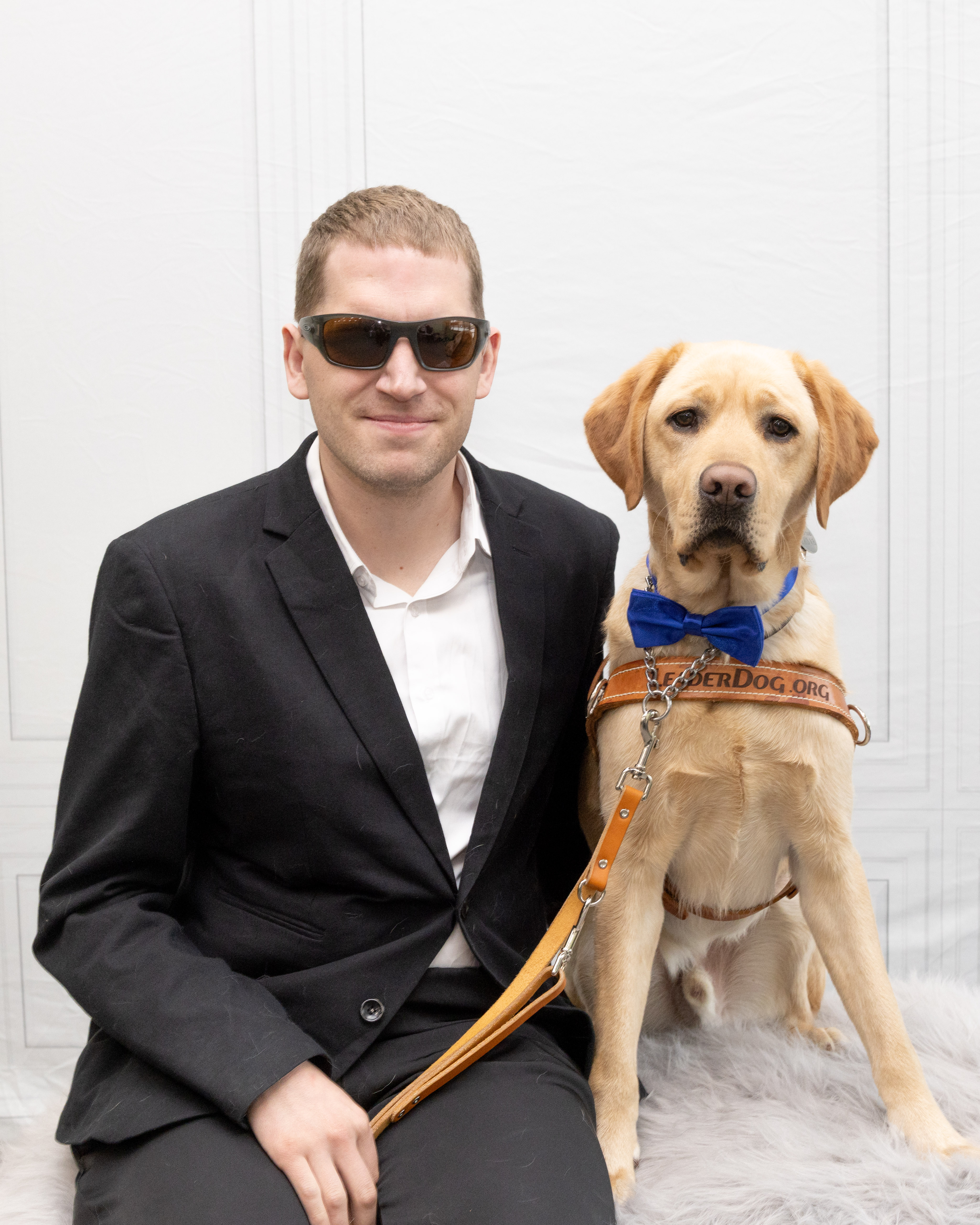 Founder of Three Monkeys Communication seated beside guide dog Kirby in a professional portrait.